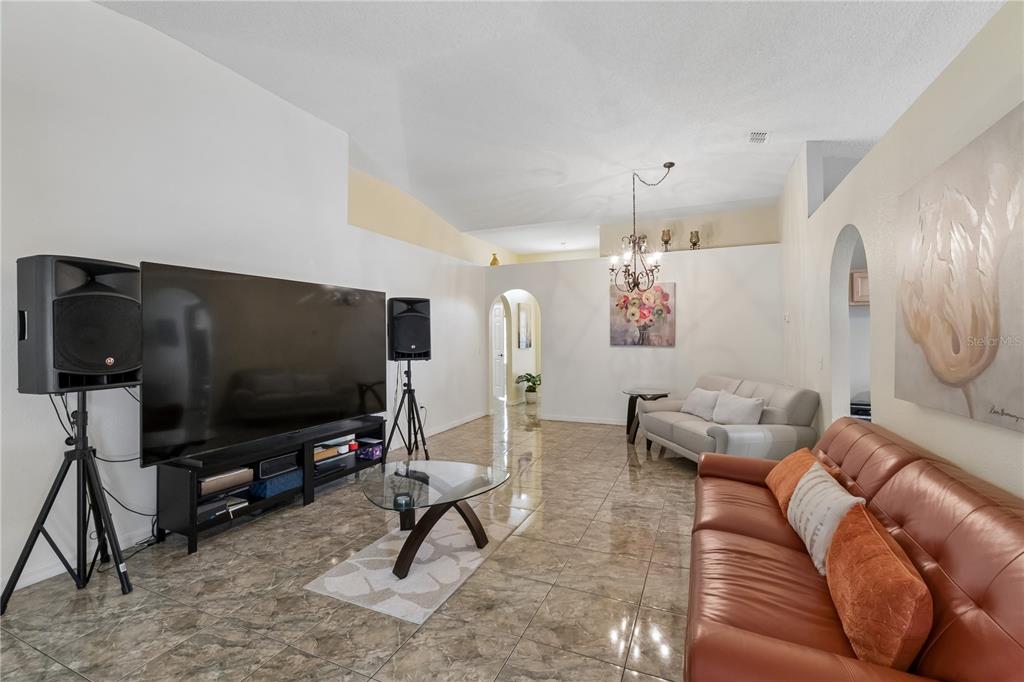 A living room features a large television, professional speakers on stands, and brown leather seating — 10354 LAXTON STREET, ORLANDO, FL