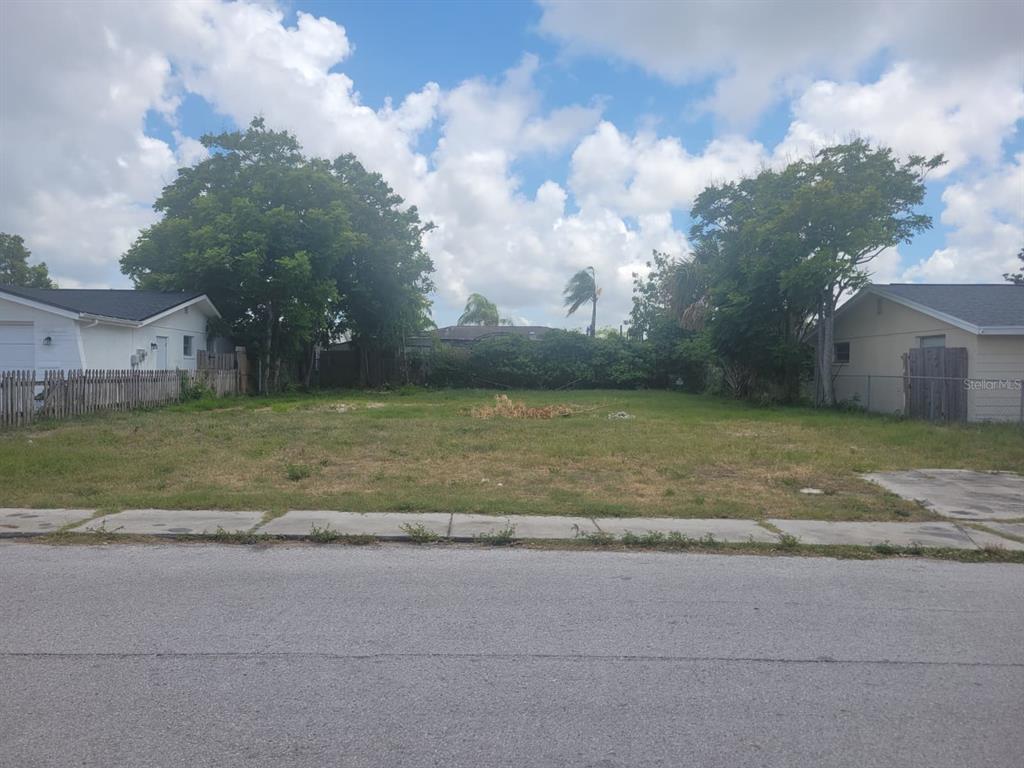 A vacant, grassy residential lot sits between two existing houses along a paved street — 7404 INGLESIDE DRIVE, PORT RICHEY, FL
