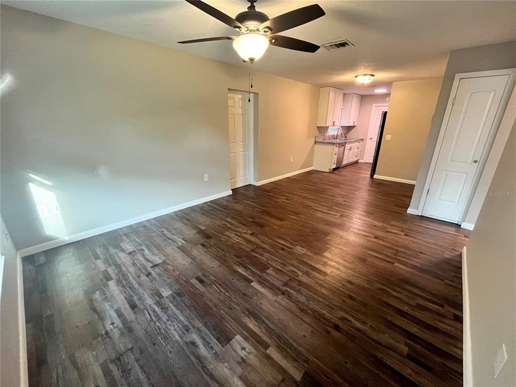 An open-concept living area features dark wood-look flooring, a ceiling fan, and an adjacent kitchen — 601 ANDYS COURT, ORANGE CITY, FL