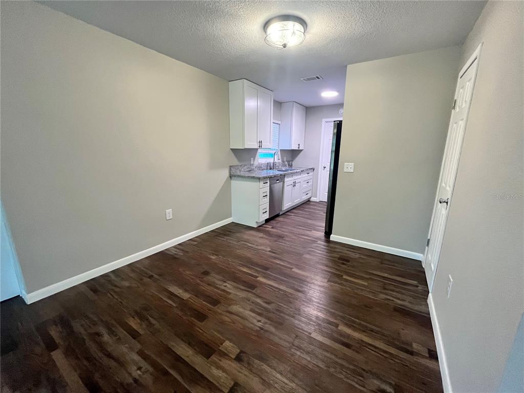 A kitchen with white cabinets, gray countertops, and dark wood-look flooring — 601 ANDYS COURT, ORANGE CITY, FL
