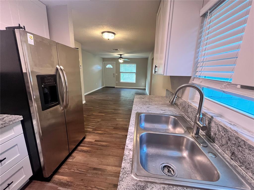 A kitchen with stainless steel appliances and granite countertops overlooks an open living area — 601 ANDYS COURT, ORANGE CITY, FL