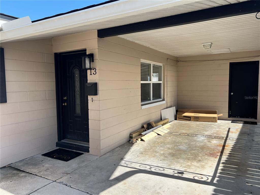 A beige exterior wall features a black front door marked 13 and a covered carport — 13 E WINTER PARK ST, ORLANDO, FL