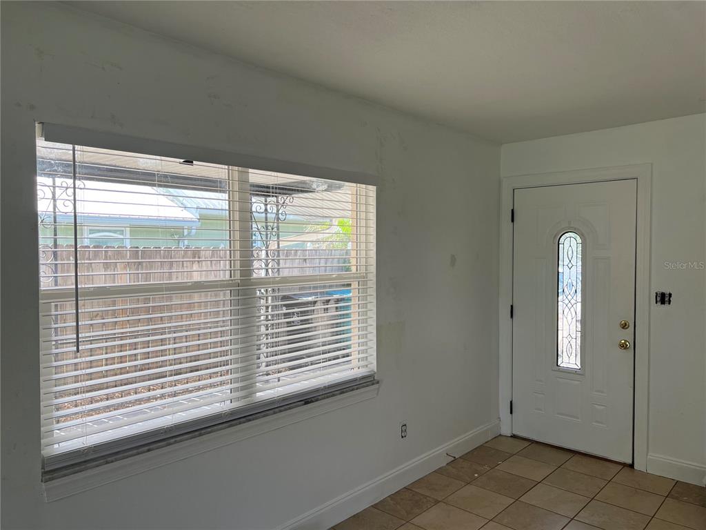 A room with tiled floors, a window with horizontal blinds, and a white front door — 13 E WINTER PARK ST, ORLANDO, FL