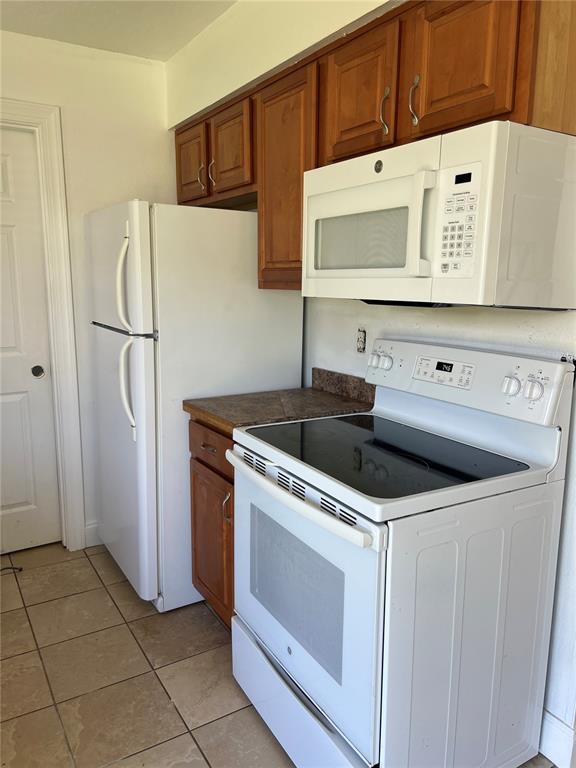 A kitchen features white appliances, wood cabinets, and tiled flooring — 13 E WINTER PARK ST, ORLANDO, FL