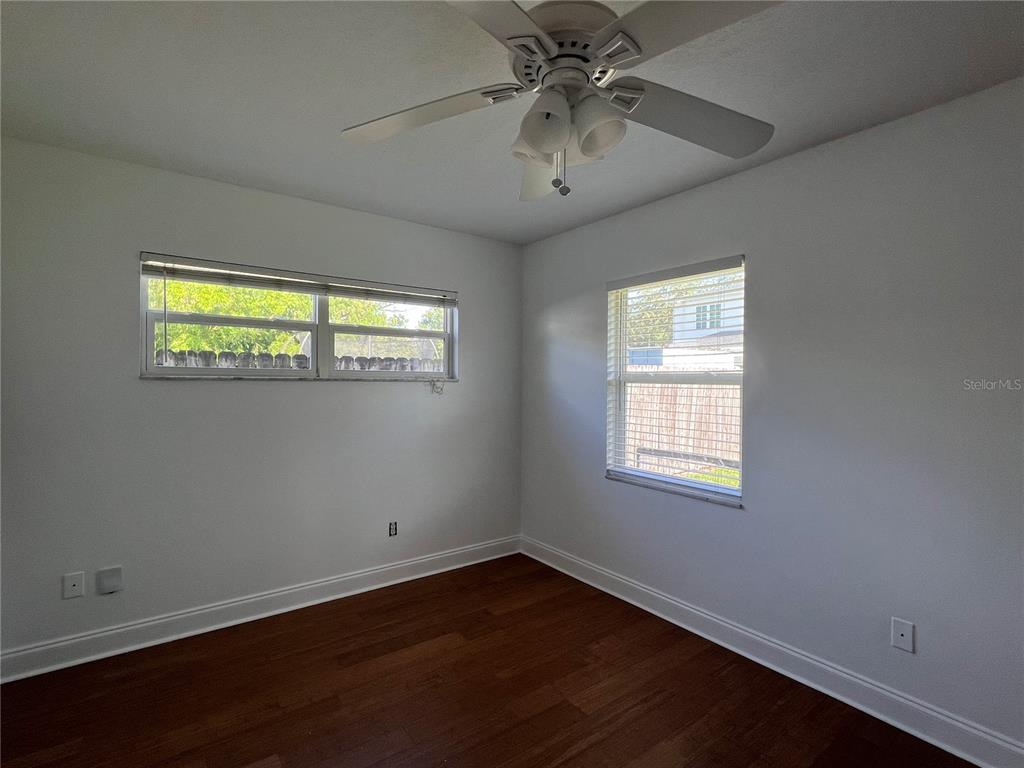 A bedroom features white walls, dark wood-look flooring, a ceiling fan, and two windows — 13 E WINTER PARK ST, ORLANDO, FL