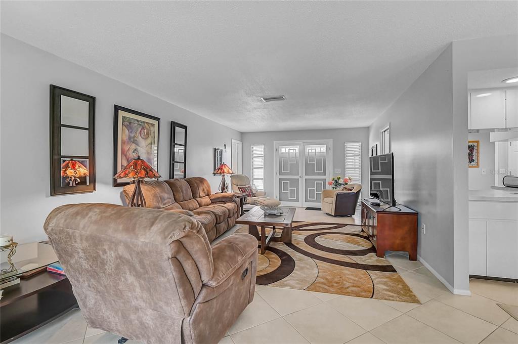 A living room features tile flooring, a brown sectional sofa, and a patterned area rug — 7128 W COUNTRY CLUB DRIVE N, SARASOTA, FL