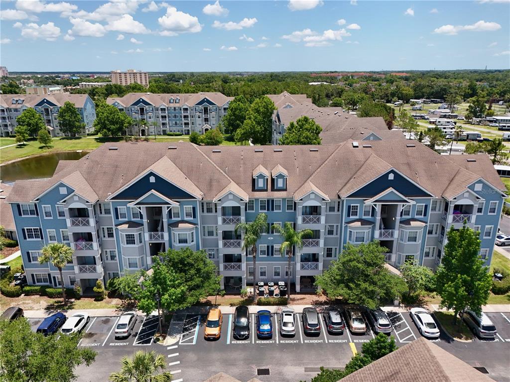 An aerial view shows a multi-story apartment building with a parking lot in front — 5255 CANE ISLAND LOOP UNIT 204, KISSIMMEE, FL