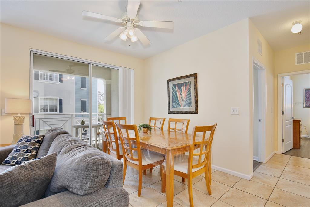 A dining area with a wooden table, six chairs, tile flooring, and a ceiling fan — 5255 CANE ISLAND LOOP UNIT 204, KISSIMMEE, FL