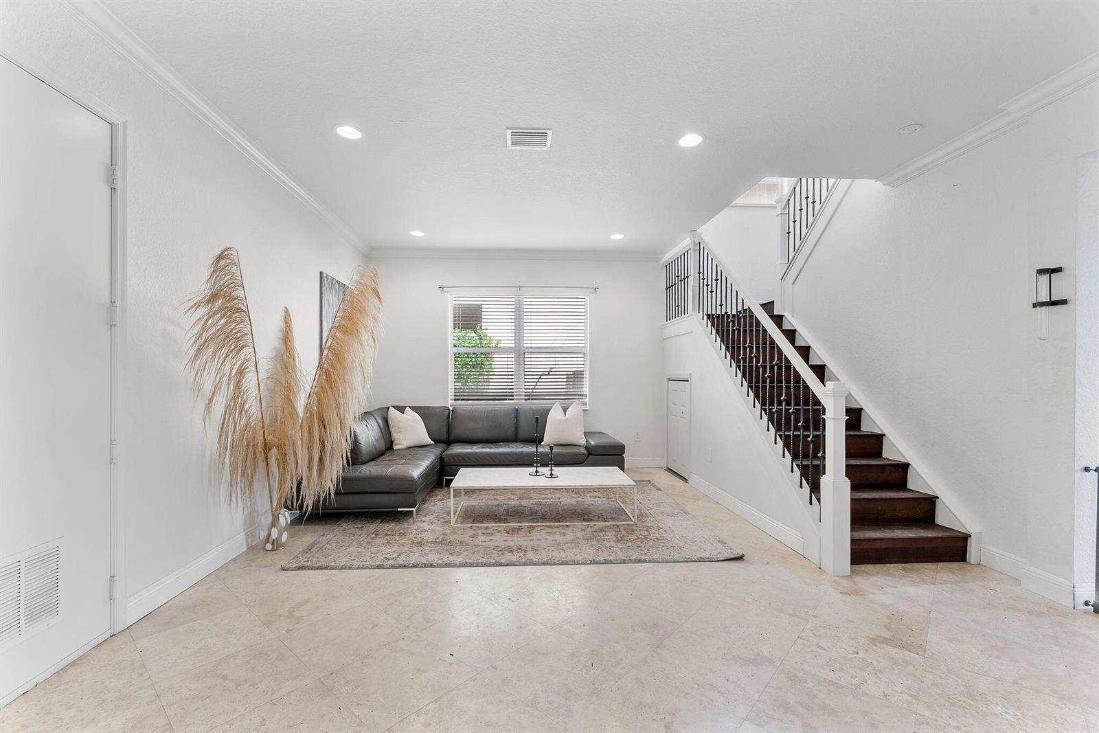 A living room features a grey sectional sofa, a coffee table, and a wooden staircase — 7942 Parsons Pine Drive, Boynton Beach FL 33437, BOYNTON BEACH, FL