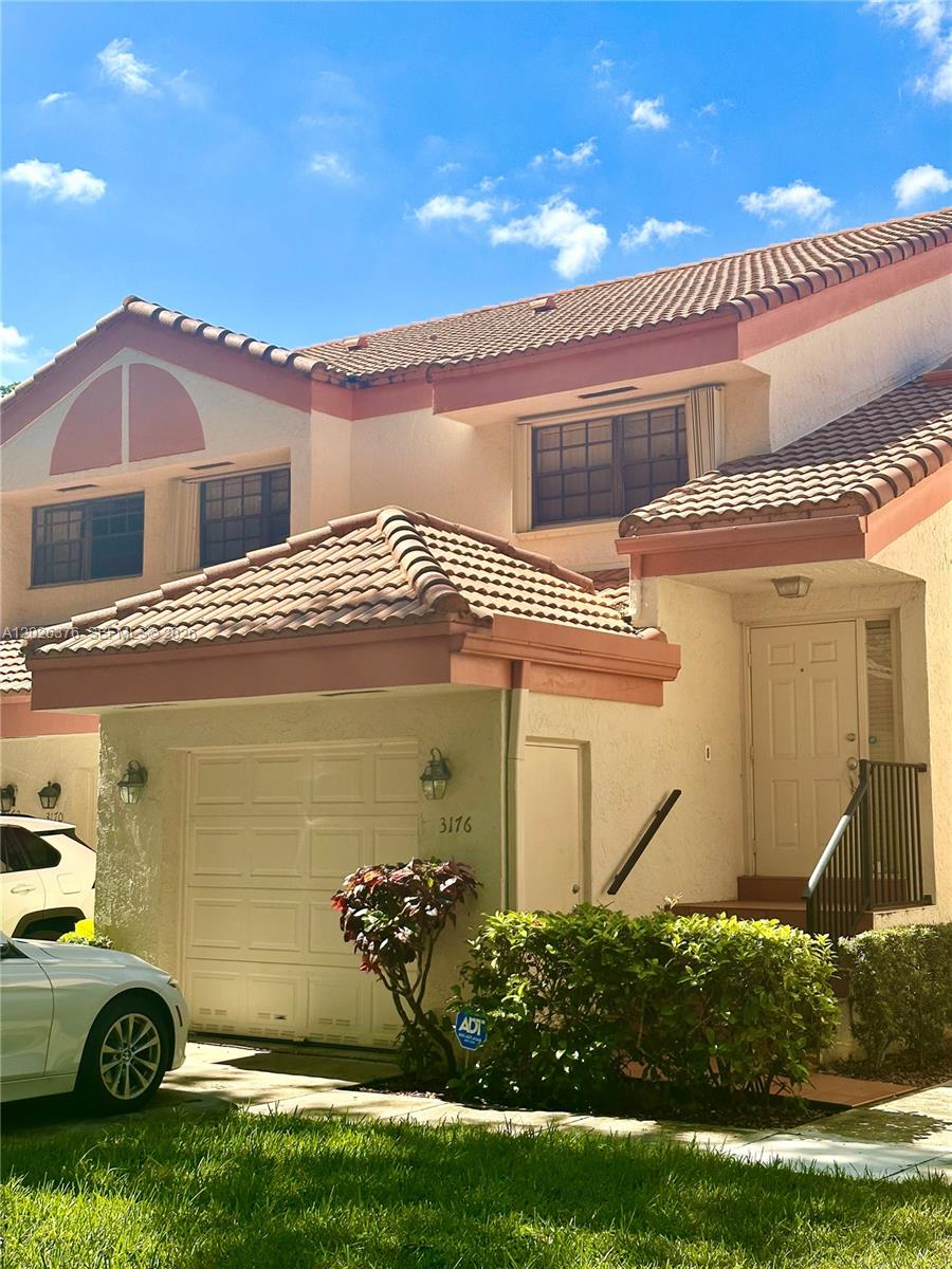 A two-story townhouse exterior features a single-car garage, a front entrance, and a tiled roof — 3176 Arbor Ln # 2506, Hollywood FL 33021, HOLLYWOOD, FL