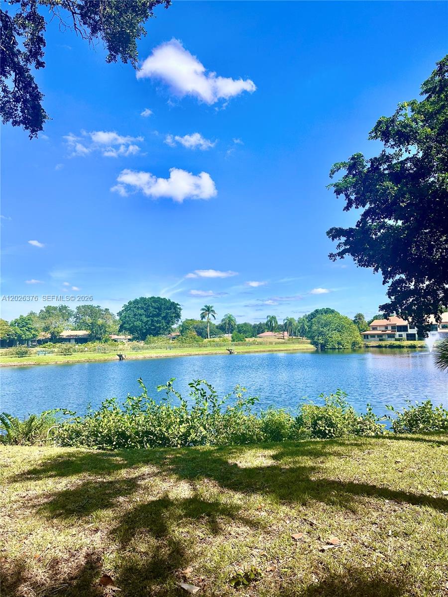 A view of a lake surrounded by trees and residential buildings under a blue sky — 3176 Arbor Ln # 2506, Hollywood FL 33021, HOLLYWOOD, FL