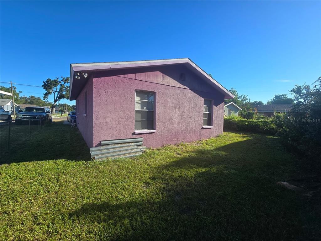 The exterior of a purple stucco house features two windows and a metal roof overhang — 503 25TH STREET E, PALMETTO, FL