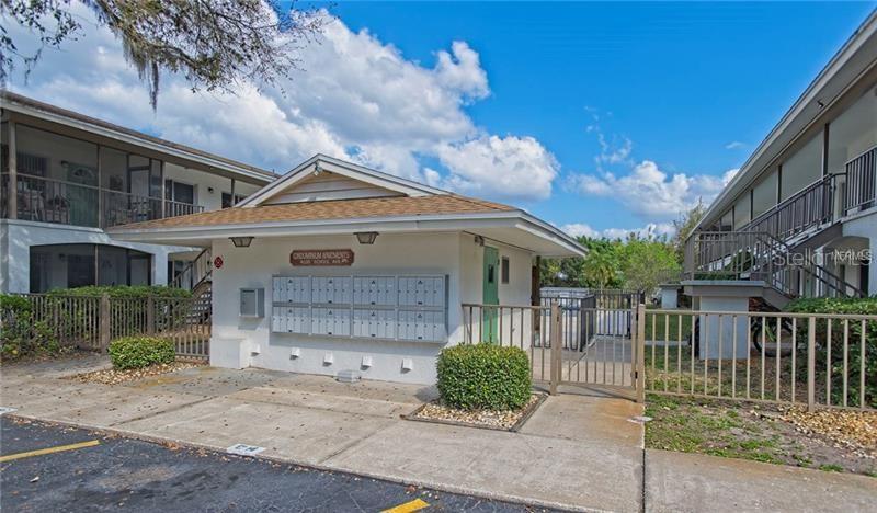 A central mailbox kiosk stands between two apartment buildings with a gated pool area behind — 4035 S SCHOOL AVENUE UNIT B10, SARASOTA, FL