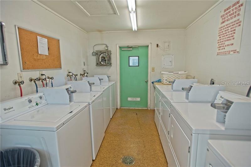 A laundry room features multiple white washing machines and dryers against white walls — 4035 S SCHOOL AVENUE UNIT B10, SARASOTA, FL