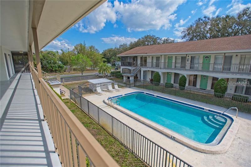 An elevated view of an apartment complex courtyard featuring a swimming pool and metal fencing — 4035 S SCHOOL AVENUE UNIT B10, SARASOTA, FL