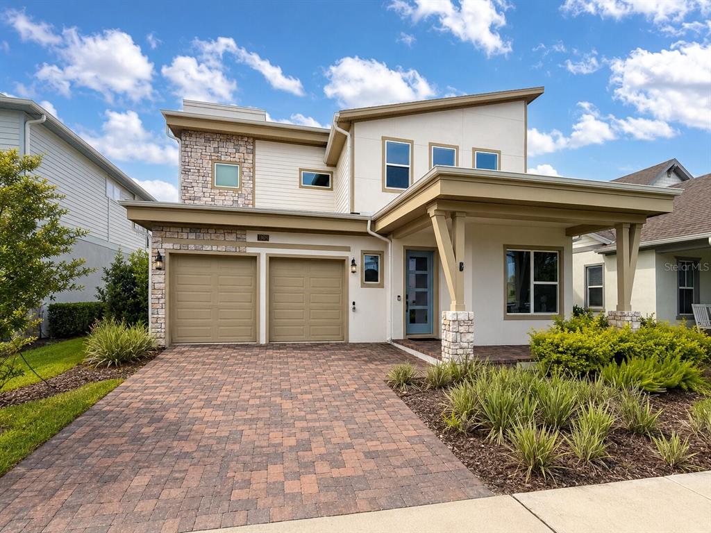 A two-story house with a stone-accented facade, a two-car garage, and a paved driveway — 13629 MCMILLAN DRIVE, ORLANDO, FL