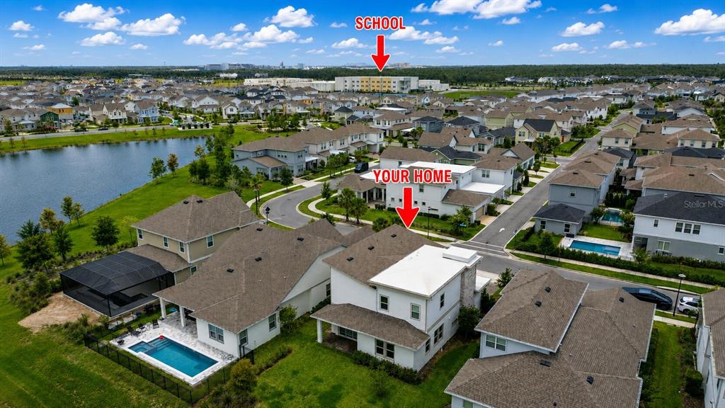 An aerial view shows a residential neighborhood with a large school building in the distance — 13629 MCMILLAN DRIVE, ORLANDO, FL