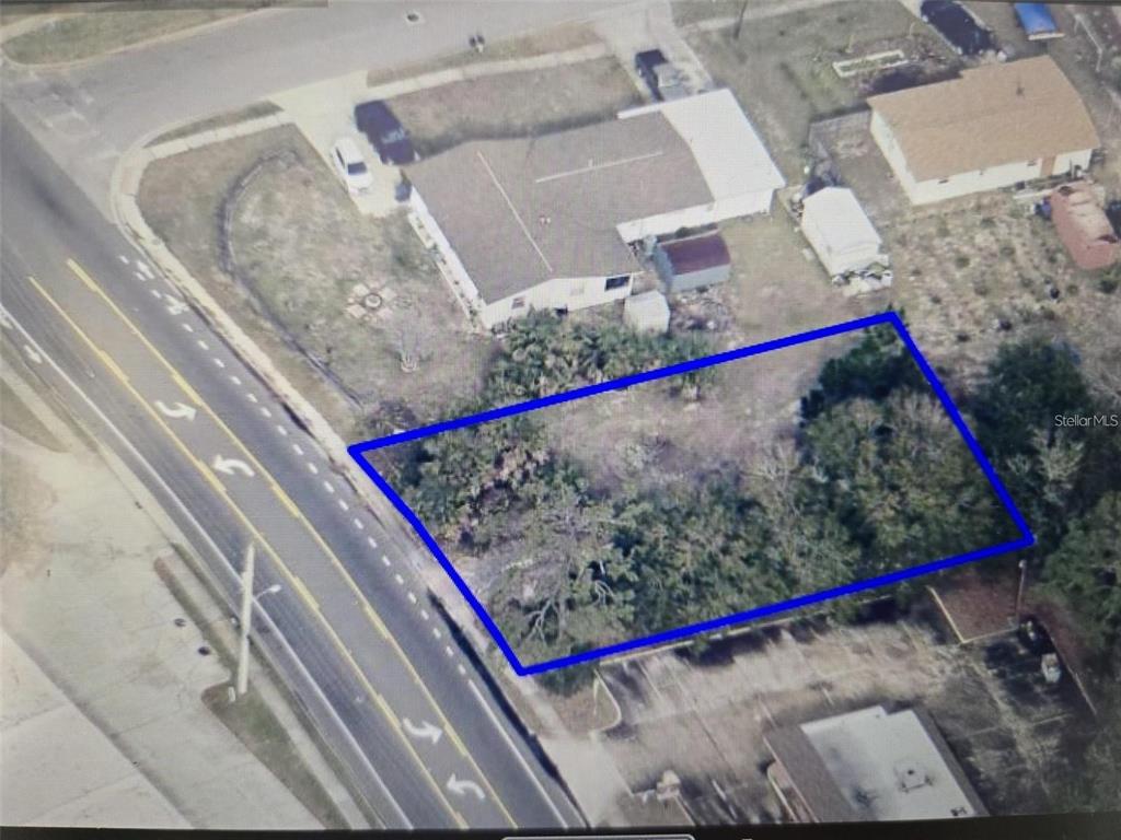 An aerial view shows a vacant, rectangular lot outlined in blue next to a residential house — 3837 S HOPKINS AVENUE, TITUSVILLE, FL