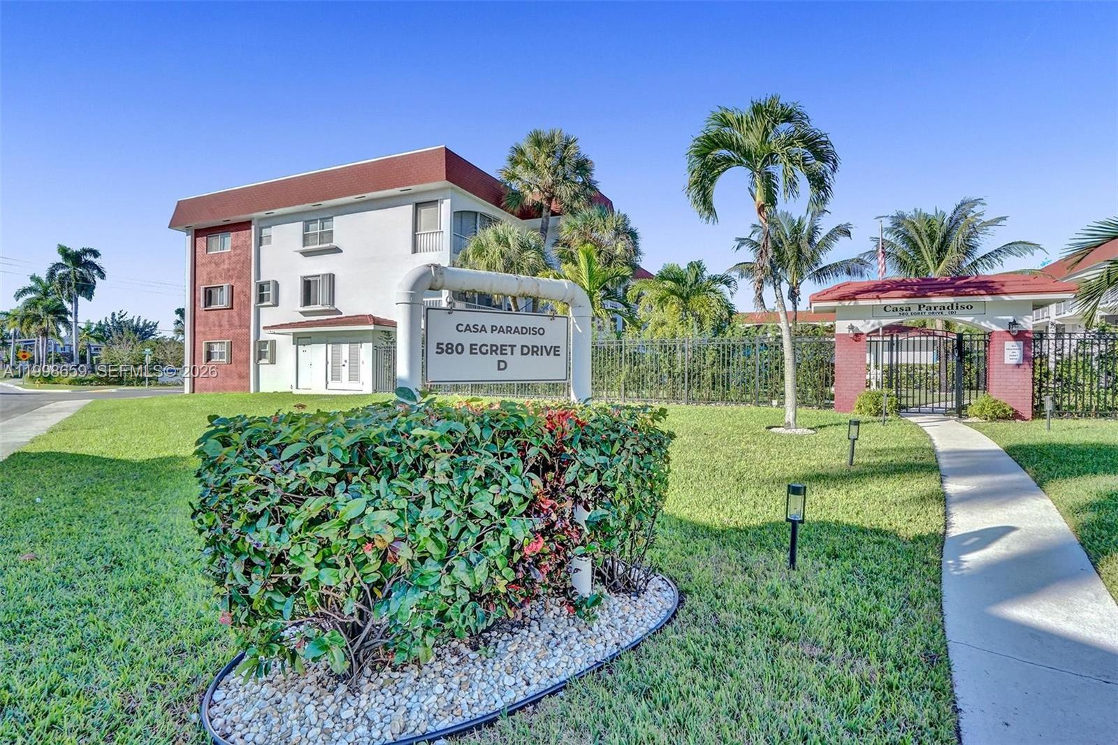 A multi-story apartment building with a sign in the foreground and a gated entrance — 580 Egret Dr # 212, Hallandale Beach FL 33009, HALLANDALE BEACH, FL