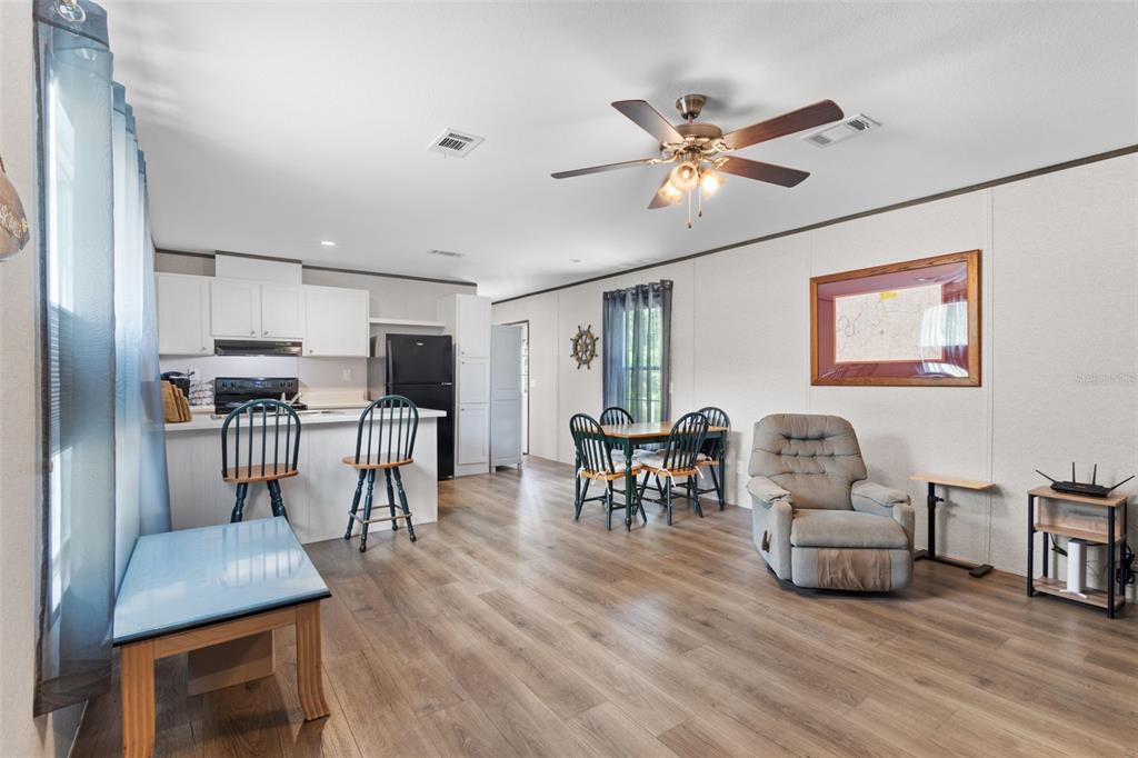 An open-concept living and dining area features light wood flooring, white cabinets, and a ceiling fan — 311 NE 316TH AVENUE, OLD TOWN, FL