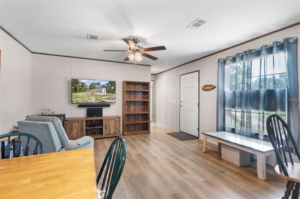 A living room features wood-look flooring, a ceiling fan, a television, and a wooden bookshelf — 311 NE 316TH AVENUE, OLD TOWN, FL