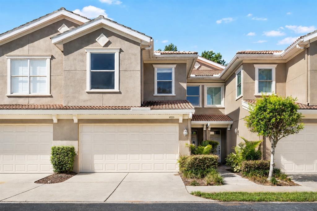 The exterior of a two-story townhouse features a beige stucco facade and a two-car garage — 4920 ANNISTON CIRCLE, TAMPA, FL