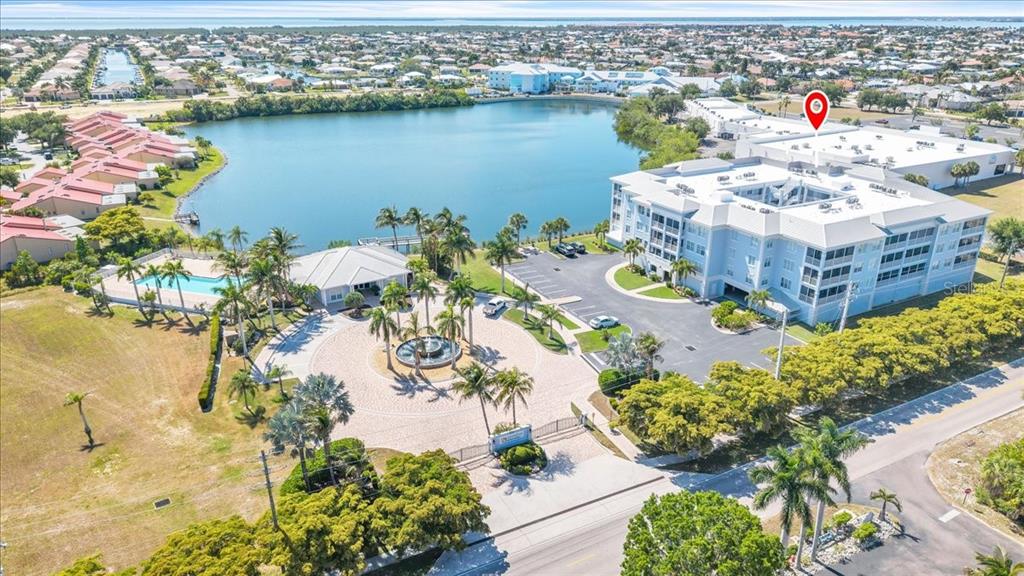 An aerial view shows a multi-story apartment building, a lake, a pool, and landscaping — 2001 BAL HARBOR BOULEVARD UNIT 2207, PUNTA GORDA, FL