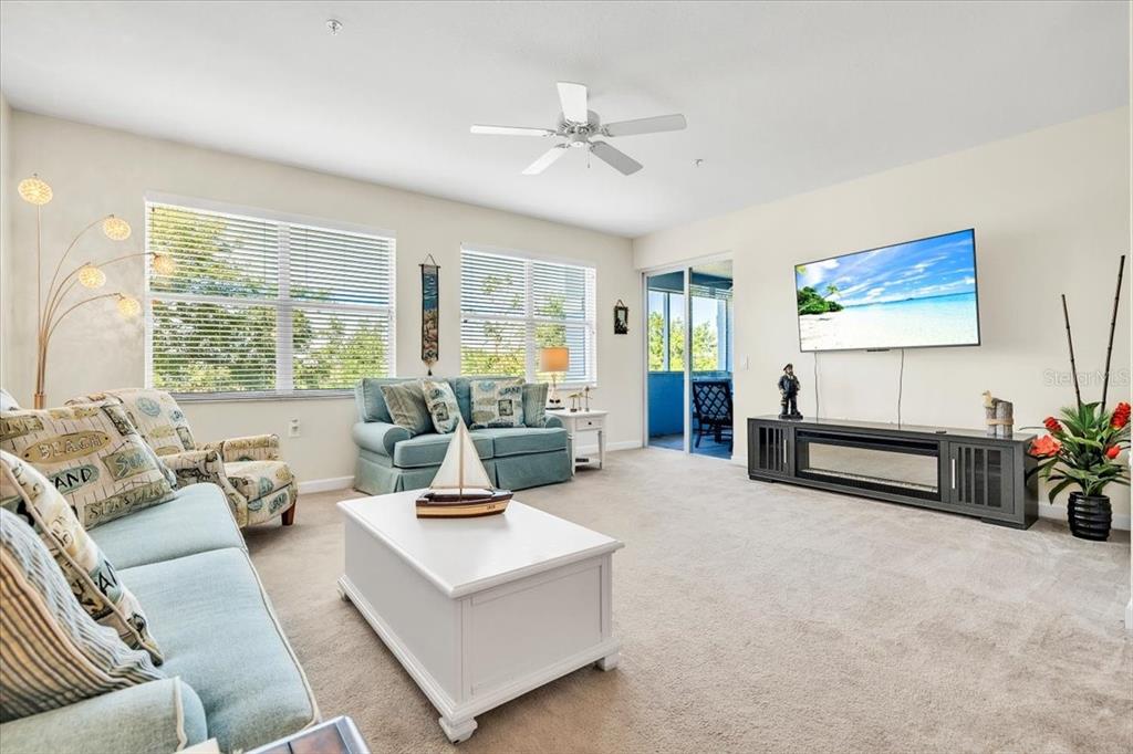 A living room features light blue sofas, a white coffee table, and a wall-mounted television — 2001 BAL HARBOR BOULEVARD UNIT 2207, PUNTA GORDA, FL