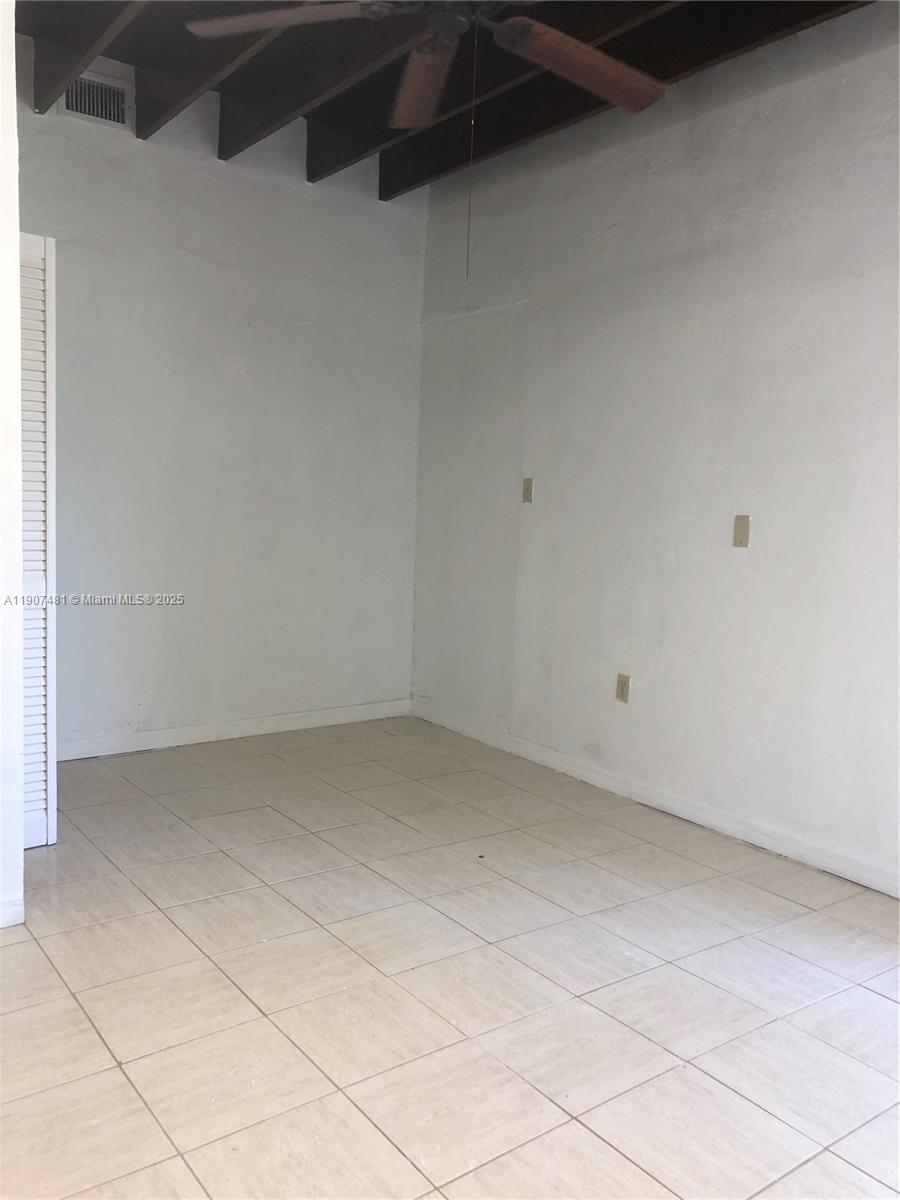 An empty room features white walls, light-colored floor tiles, and an exposed wood-beam ceiling — 1374 NE 176 st # 3, North Miami Beach FL 33162, NORTH MIAMI BEACH, FL