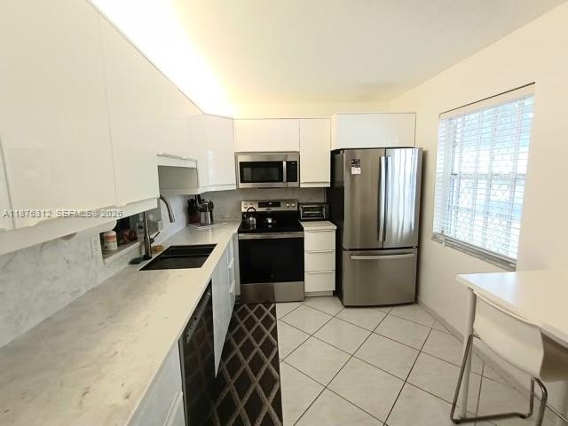 A modern kitchen features white cabinets, stainless steel appliances, and light-colored countertops and flooring — 1025 SE 4th Ave # 101, Dania Beach FL 33004, DANIA BEACH, FL