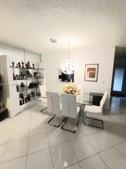 A bright, tiled living room features a large mirrored wall and a modern pendant light — 1025 SE 4th Ave # 101, Dania Beach FL 33004, DANIA BEACH, FL
