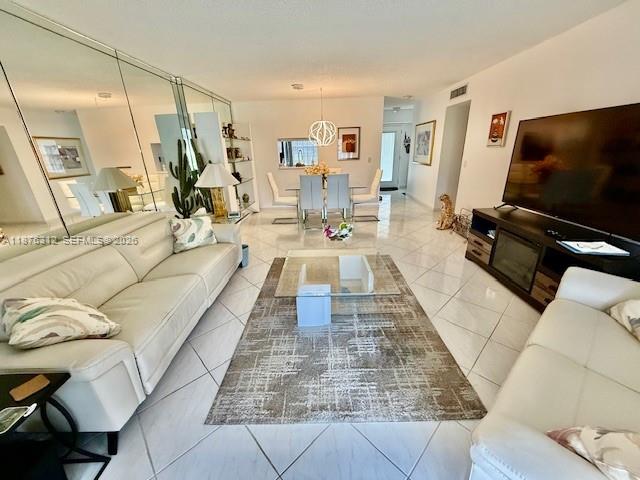 A bright, empty living room features white tiled floors, mirrored walls, and sliding glass doors — 1025 SE 4th Ave # 101, Dania Beach FL 33004, DANIA BEACH, FL