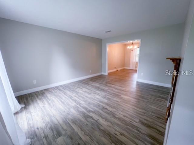 An empty room with light gray walls and wood-look flooring leads into an adjacent space — 1928 LAWSON ROAD, TALLAHASSEE, FL