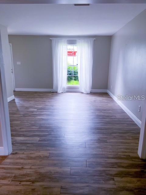 An empty room features light wood-look flooring, gray walls, and a window with white curtains — 1928 LAWSON ROAD, TALLAHASSEE, FL