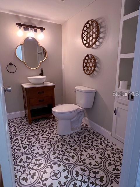 A bathroom features a patterned tile floor, a wooden vanity, and a wall-mounted toilet — 1928 LAWSON ROAD, TALLAHASSEE, FL