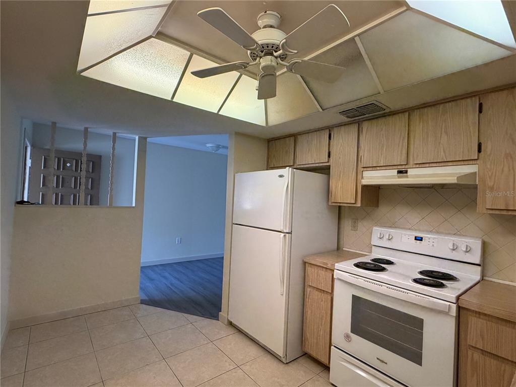 A kitchen features light wood cabinets, white appliances, tiled flooring, and a recessed ceiling fan — 9221 REPONDO PL, NEW PORT RICHEY, FL
