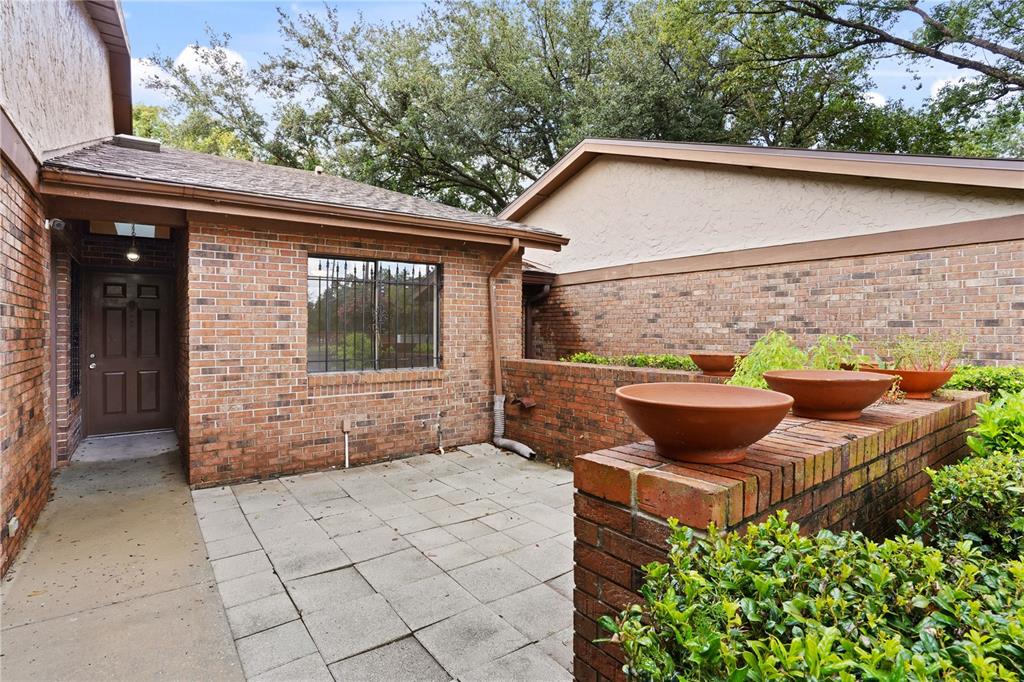 A brick exterior home features a paved patio, a front door, and decorative planter bowls — 302 SAND TRAP COVE UNIT 302, LONGWOOD, FL
