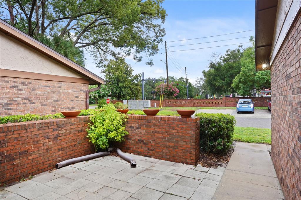 A brick-walled patio features a paved floor, potted plants, and a view of a parking lot — 302 SAND TRAP COVE UNIT 302, LONGWOOD, FL
