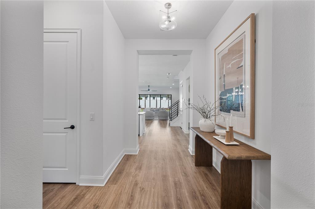 A bright hallway features wood-look flooring, a wooden console table, and a large framed print — 2403 DERBYSHIRE AVENUE, LAKELAND, FL