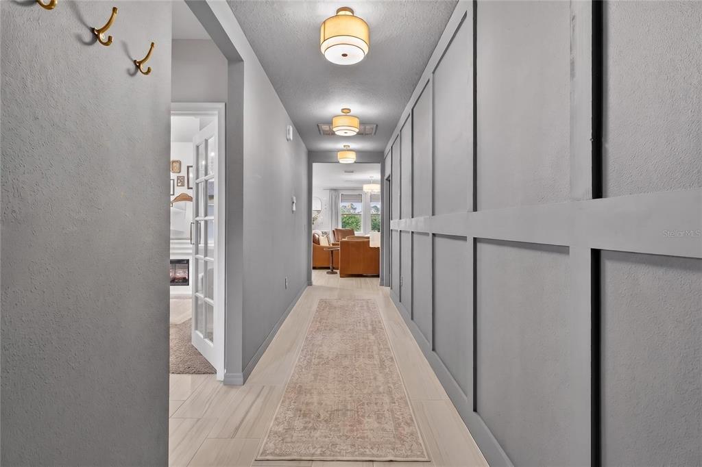 A hallway features gray board-and-batten walls, light tile flooring, and three flush-mount ceiling lights — 1256 OAK VALLEY DRIVE, AUBURNDALE, FL