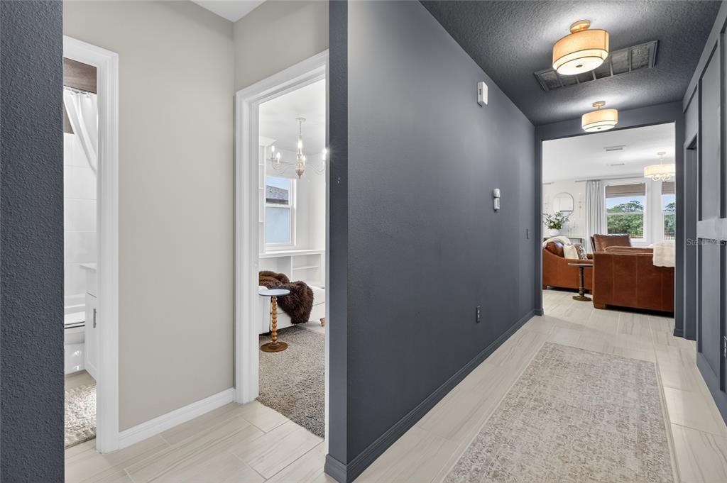 A hallway with dark gray walls and light tile flooring leads to a living area — 1256 OAK VALLEY DRIVE, AUBURNDALE, FL