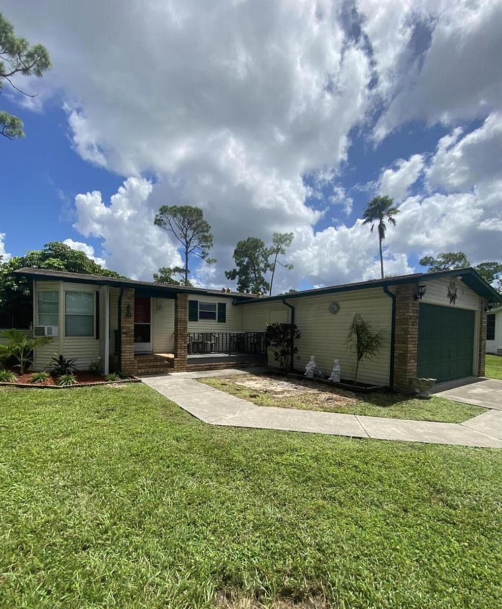A single-story house with beige siding, a green garage door, and a front porch — 19418 Saddlebrook Court, FL 33903, FL