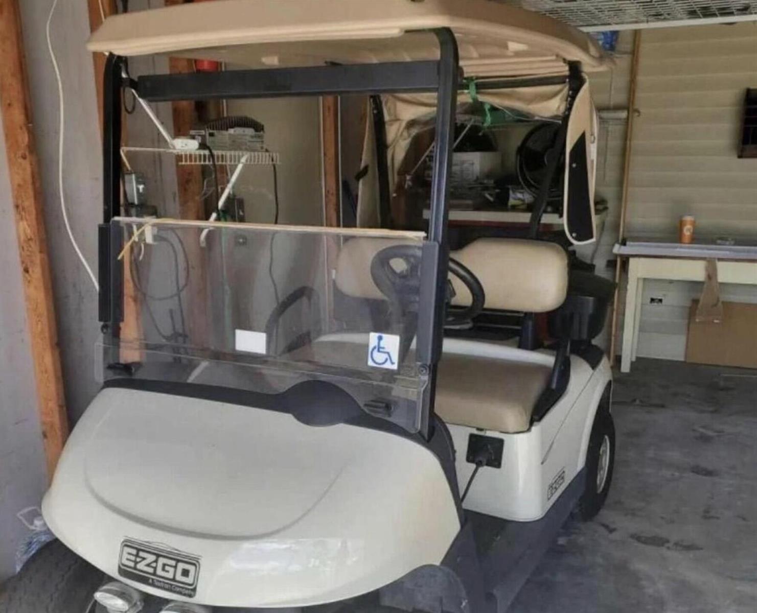 A white EZGO golf cart with a tan roof is parked inside a garage — 19418 Saddlebrook Court, FL 33903, FL