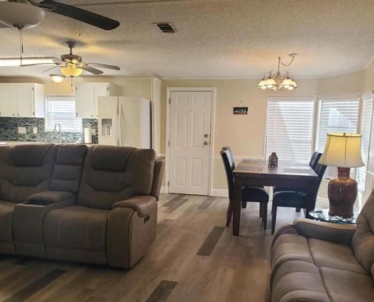 An open-concept living and dining area features wood-look flooring, neutral walls, and white cabinetry — 19418 Saddlebrook Court, FL 33903, FL