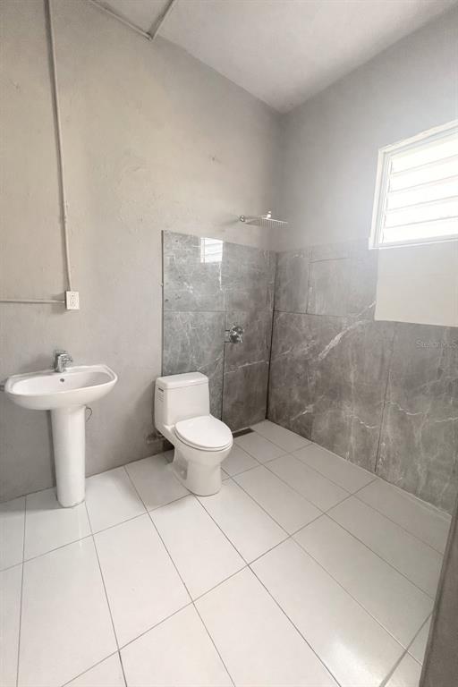 A bathroom features a pedestal sink, a white toilet, and gray marble-look tiled walls — Manuel A Padilla BO PUEBLO, TOA BAJA, PR
