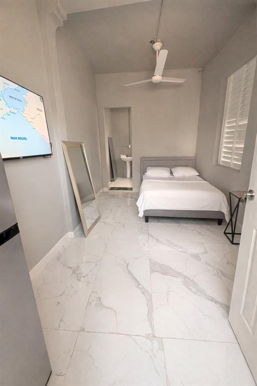 A bedroom with a bed, a ceiling fan, a floor mirror, and white marble-look flooring — Manuel A Padilla BO PUEBLO, TOA BAJA, PR