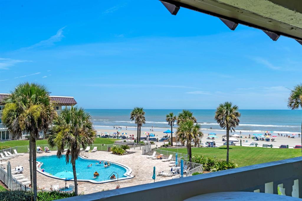 An elevated view of a swimming pool, palm trees, and a beach with the ocean — 3663 S ATLANTIC AVENUE UNIT 31B, NEW SMYRNA BEACH, FL