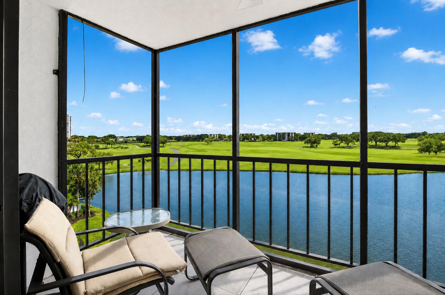 A screened-in balcony overlooks a lake and a golf course under a blue sky — 7768 Lakeside Boulevard # 551, Boca Raton FL 33434, BOCA RATON, FL