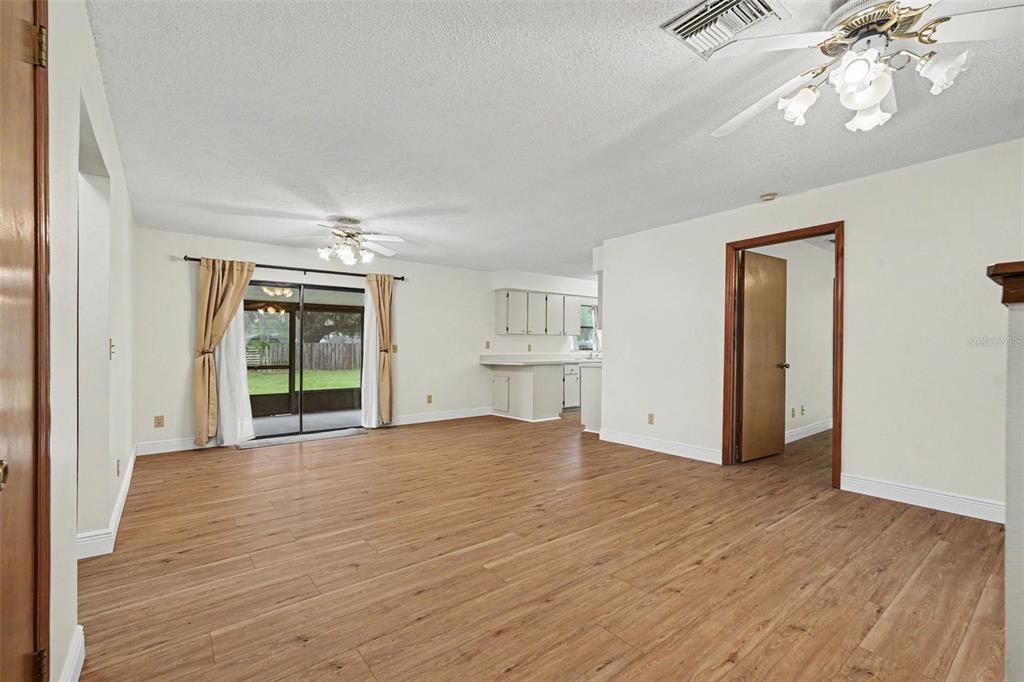 An open-concept living area with wood-look flooring, a ceiling fan, and sliding glass patio doors — 1464 SW 69TH ROAD, BUSHNELL, FL