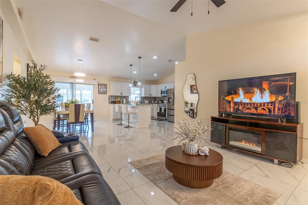 A living room with white tile floors, a leather sofa, and an open-concept kitchen — 930 HICKS ROAD, LAKELAND, FL